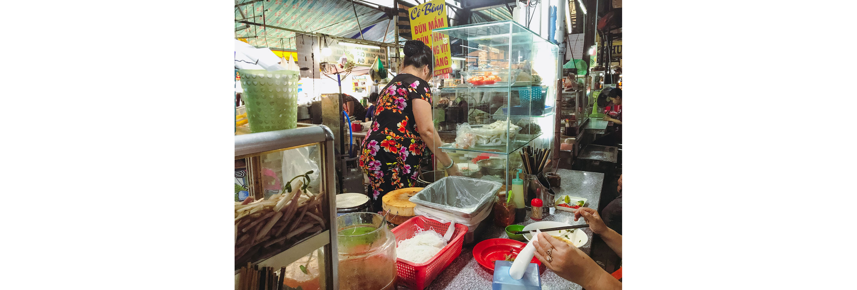 A person sitting at the counter of a busy food stall.