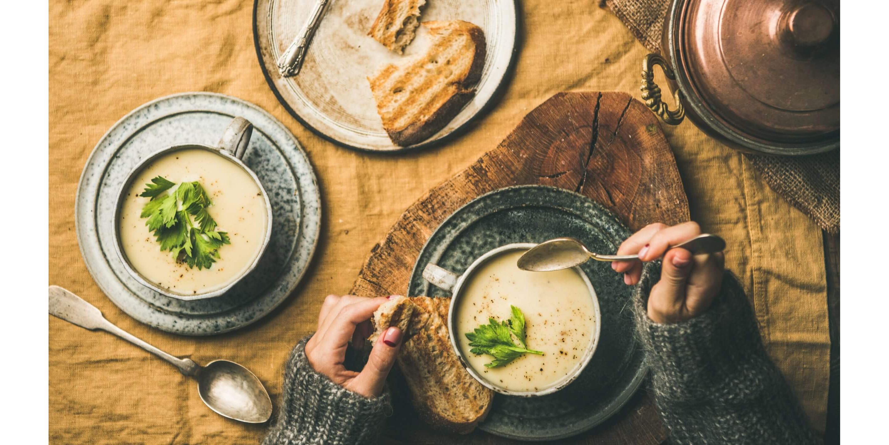 A woman enjoying a bowl of creamy soup with a side of toasted bread.