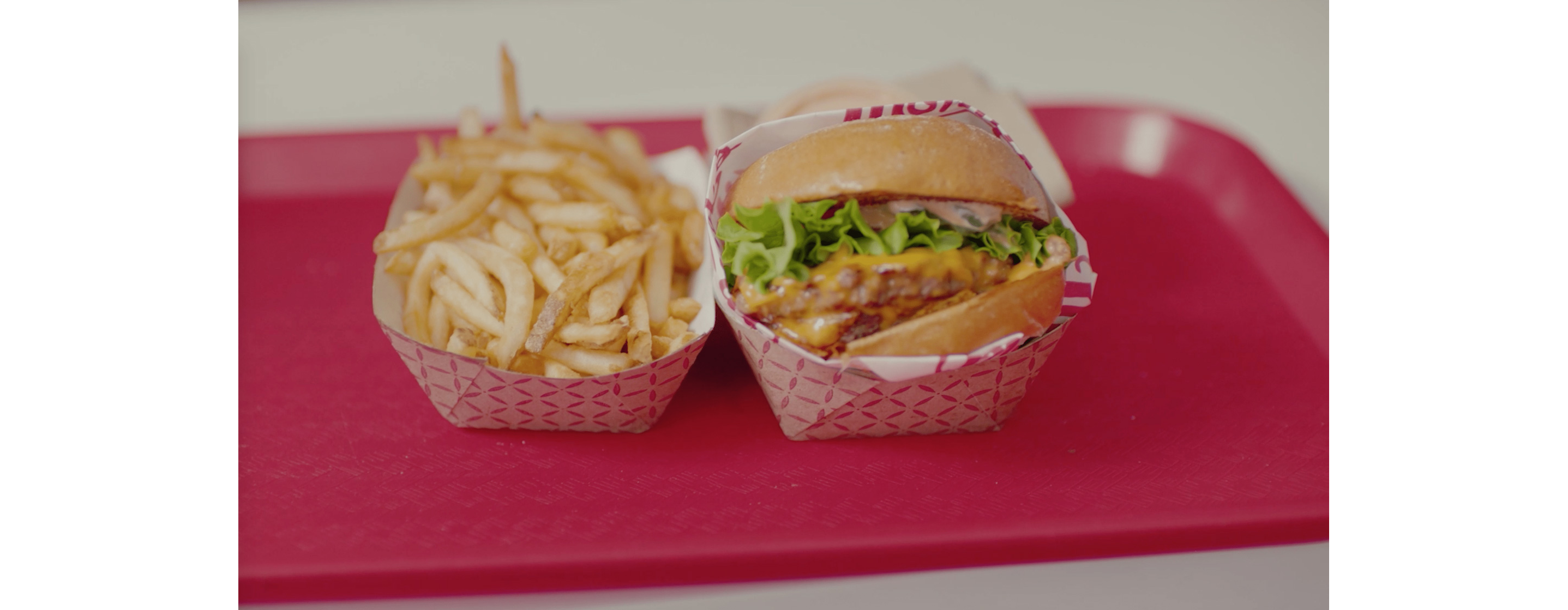 Two small paper baskets filled with french fries and a vegan burger.