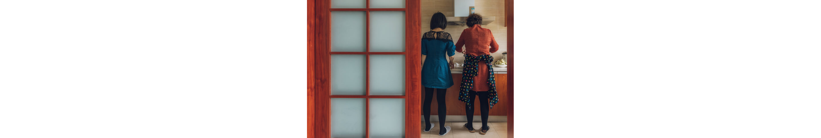 "Two women standing side by side as they focus on the cooking task at hand."