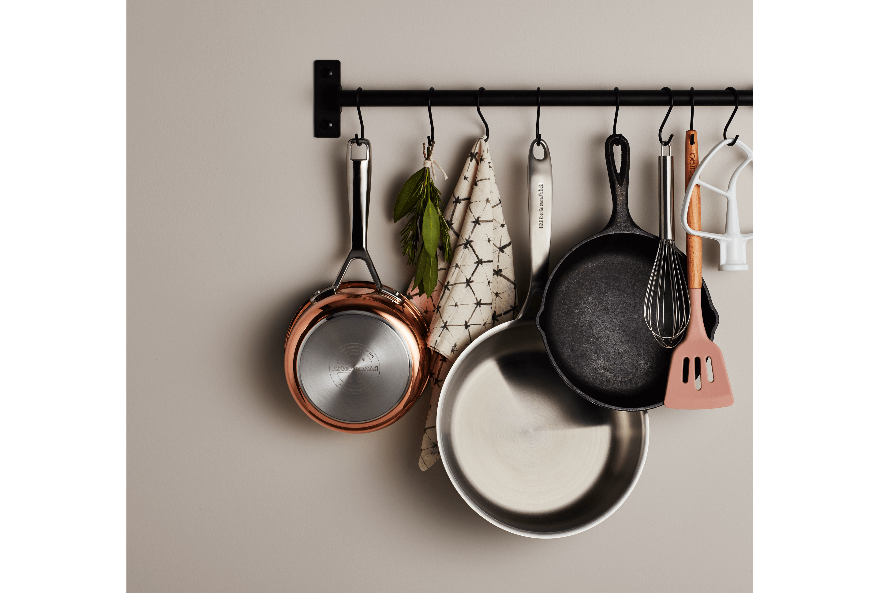 A collection of assorted pans and cookware hanging from a wall-mounted pot rack.