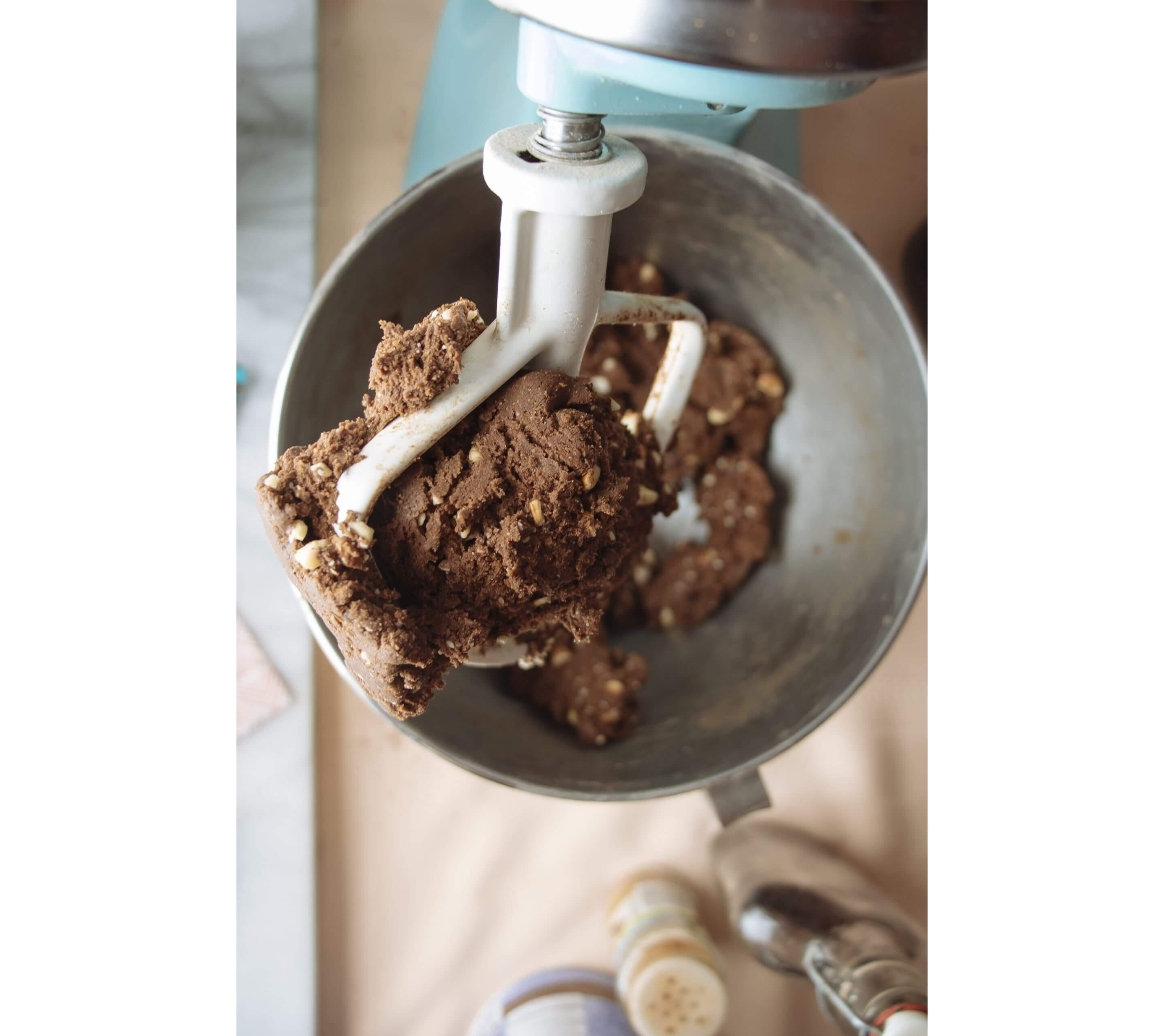 An overhead close-up of a mixer attachment doused in freshly made dough.