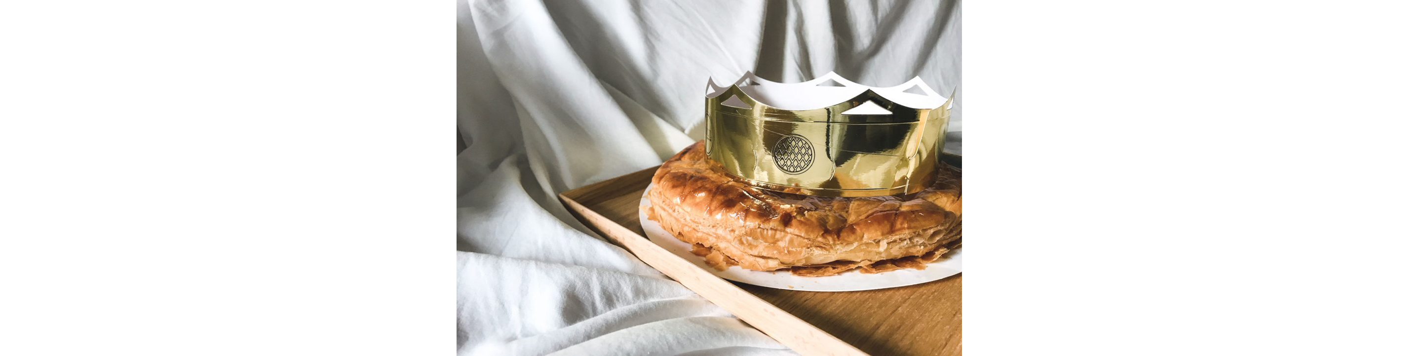 A buttery galette des rois adorned with a shiny paper crown.