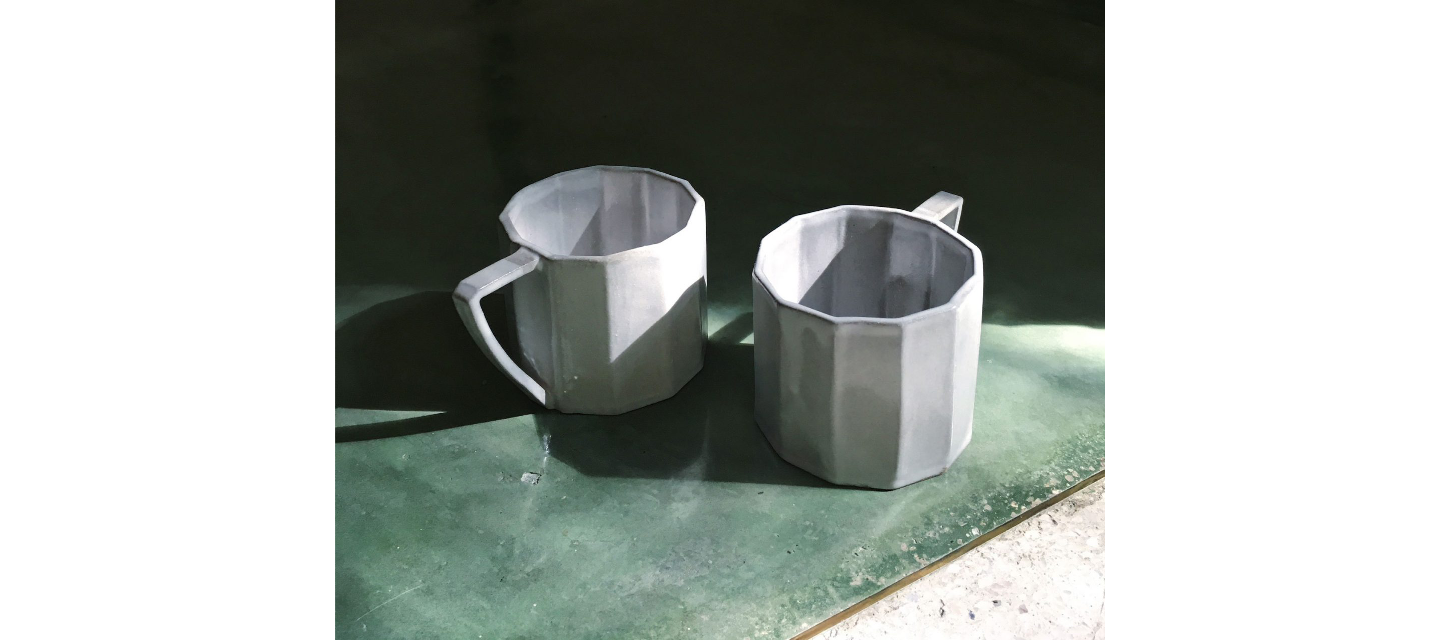 Two white ceramic coffee cups resting on a table.