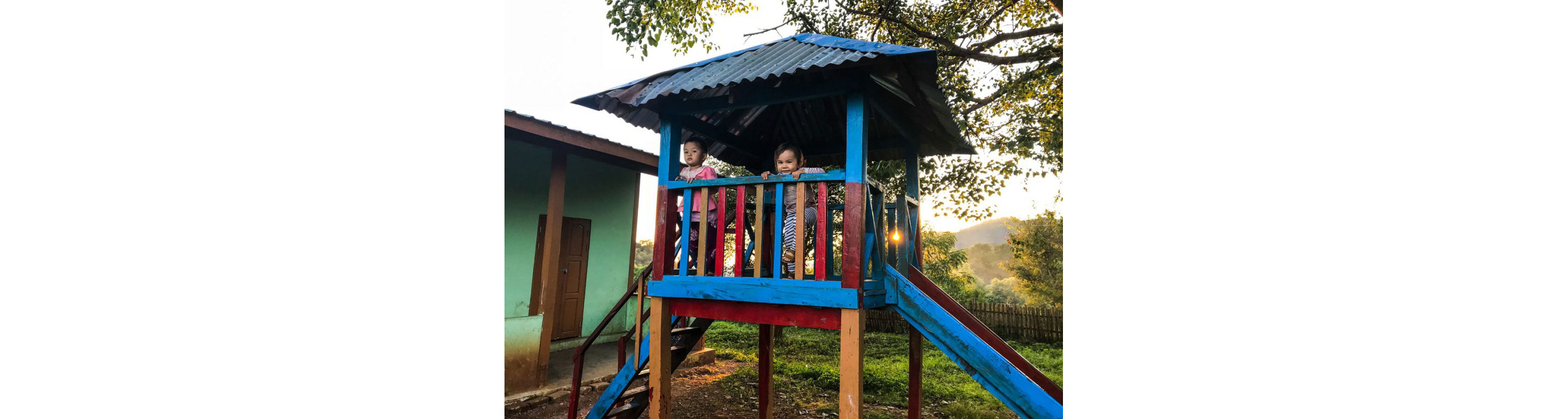Two children playing on a blue and red playset.