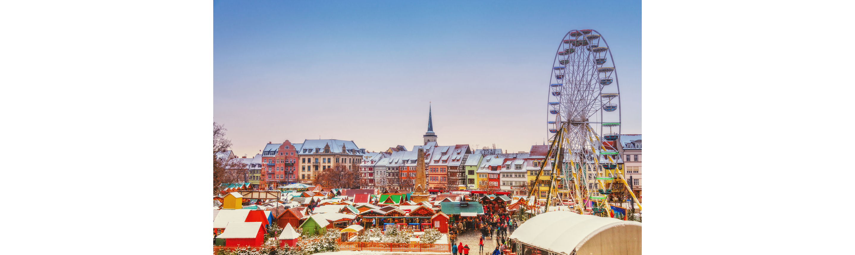 A crowded Christmas market with a ferris wheel.
