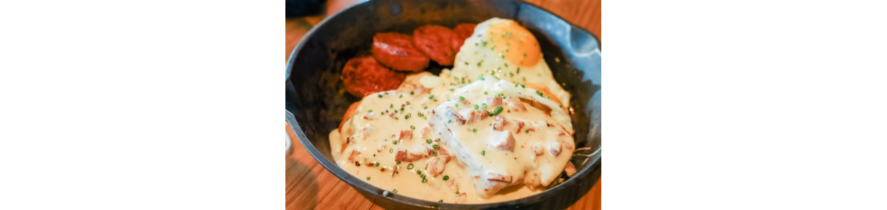 A dark bowl filled with biscuits and gravy.