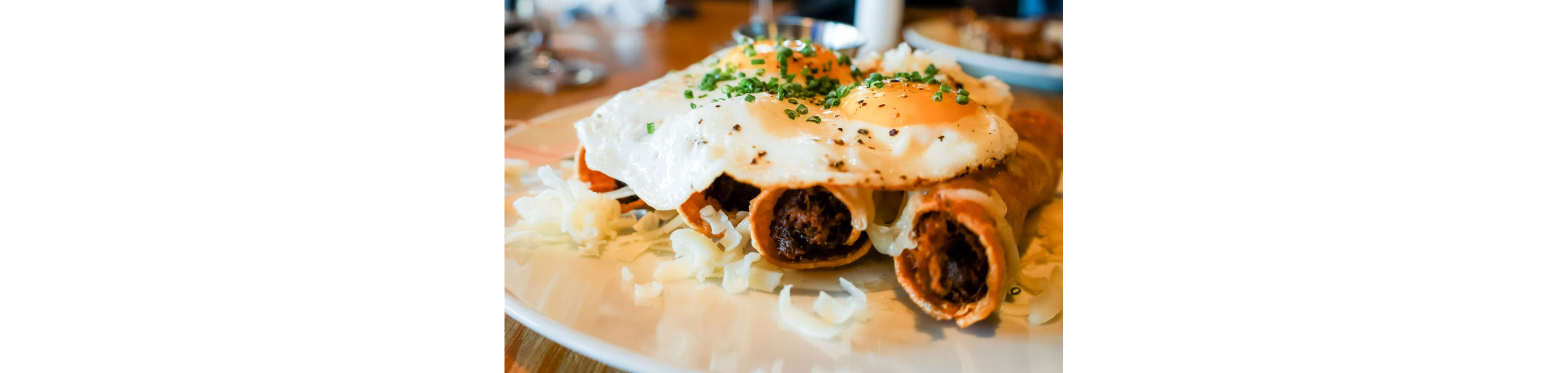 A plate of taquitos topped with a fried egg.