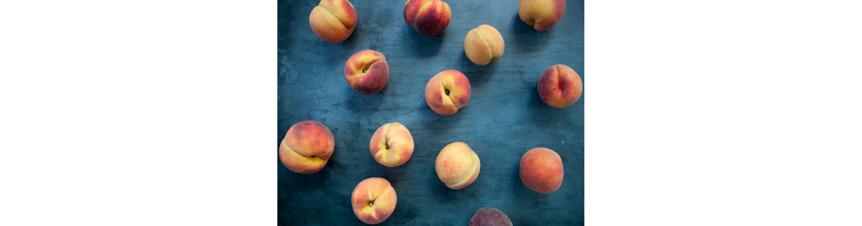 Peaches scattered along a large blue table.