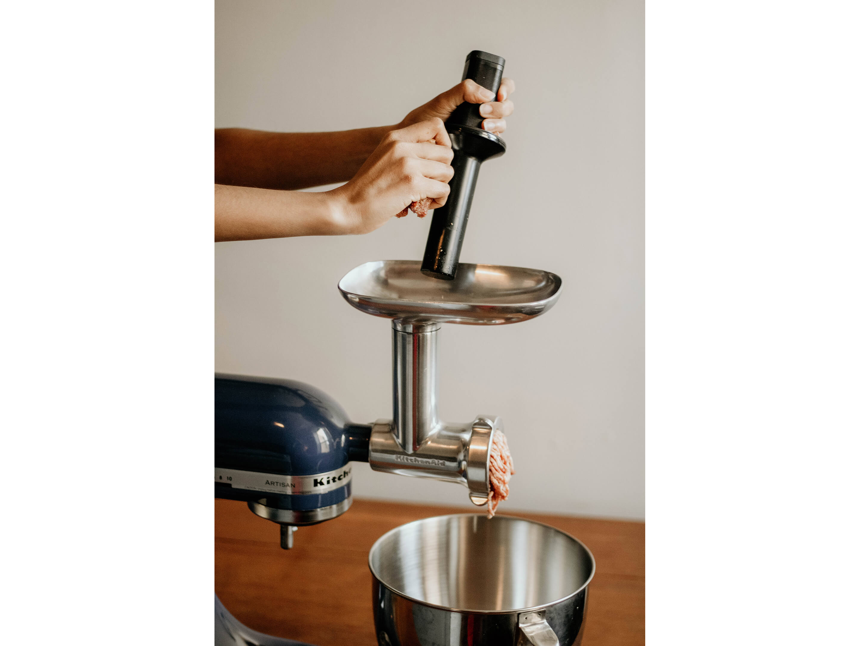 A KitchenAid® stand mixer with gently grinding meat with a food grinder attachment.