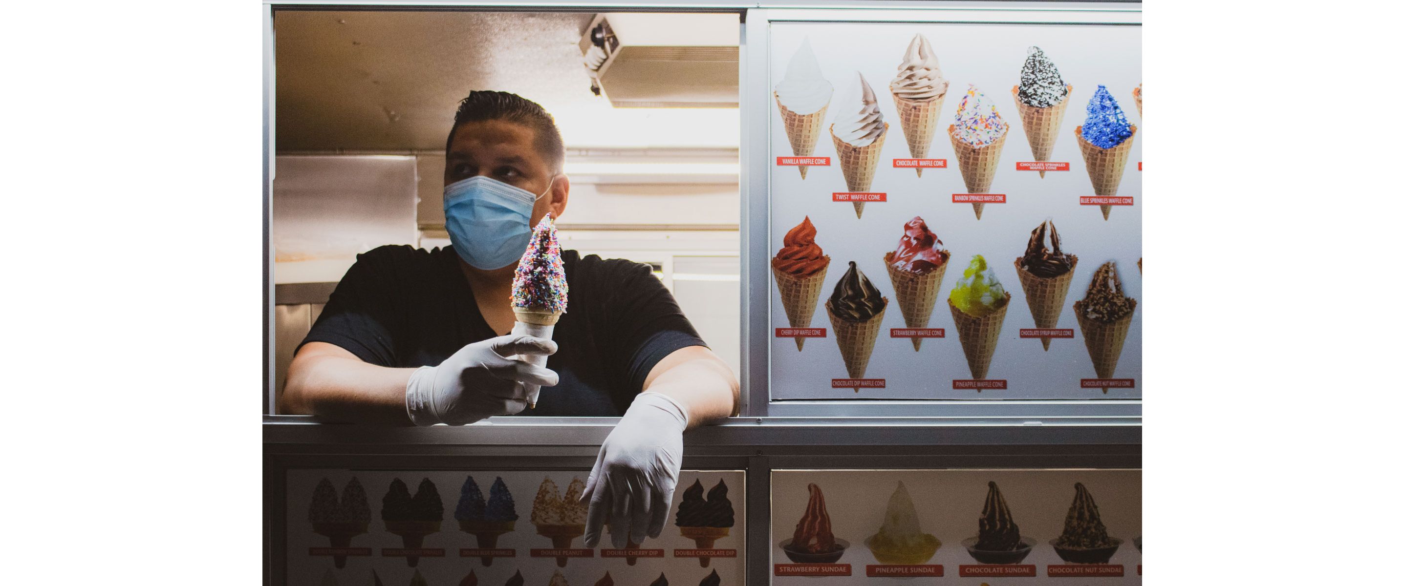 Andy Alvarez inside his ice cream truck holding an ice cream cone loaded with sprinkles.