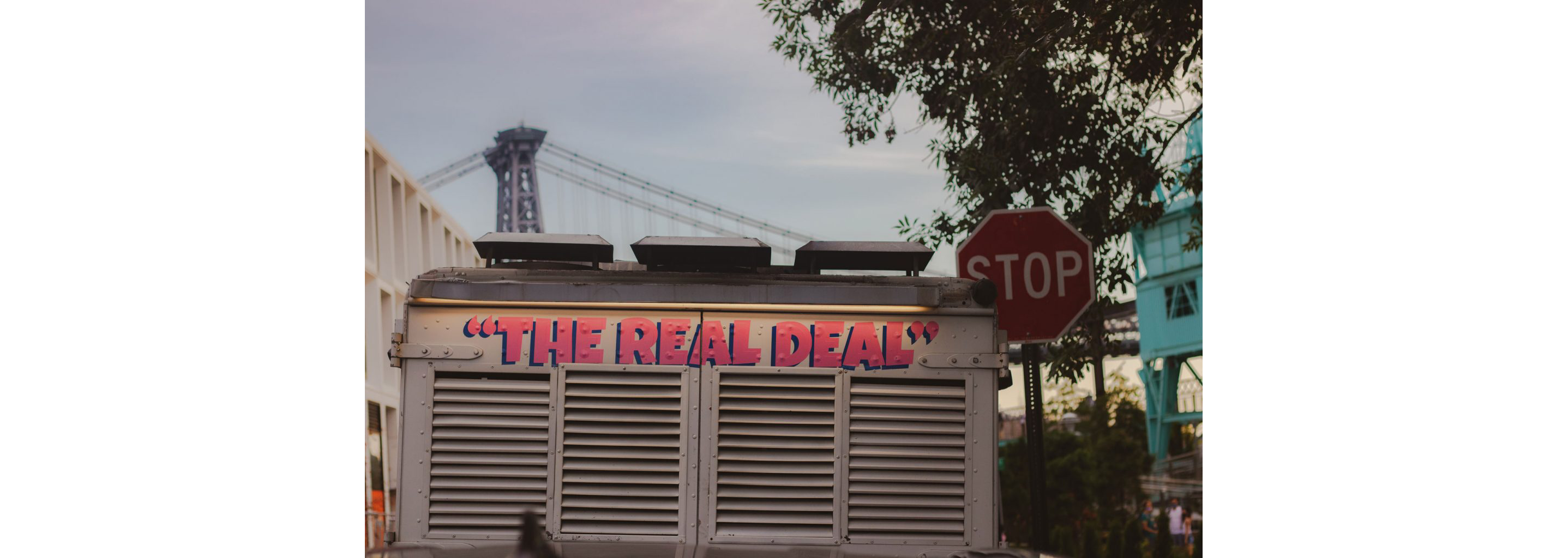 The back of an ice cream truck labeled with "The Real Deal" in bright pink.