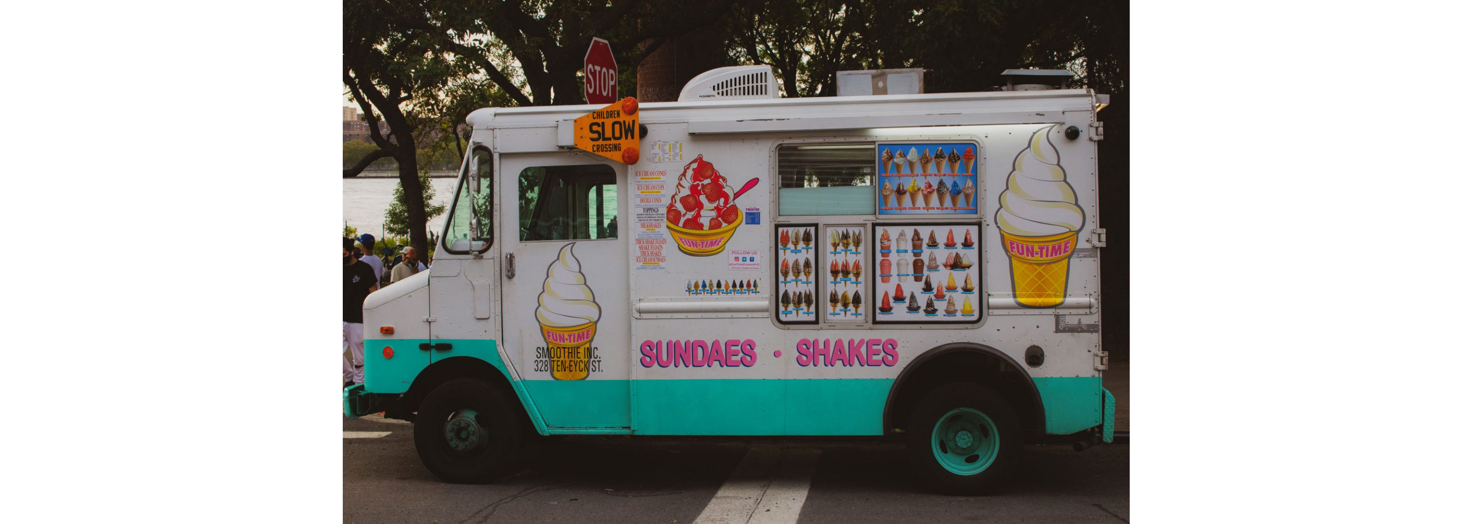 A white ice cream truck decked out with colorful, bright ice cream signage.