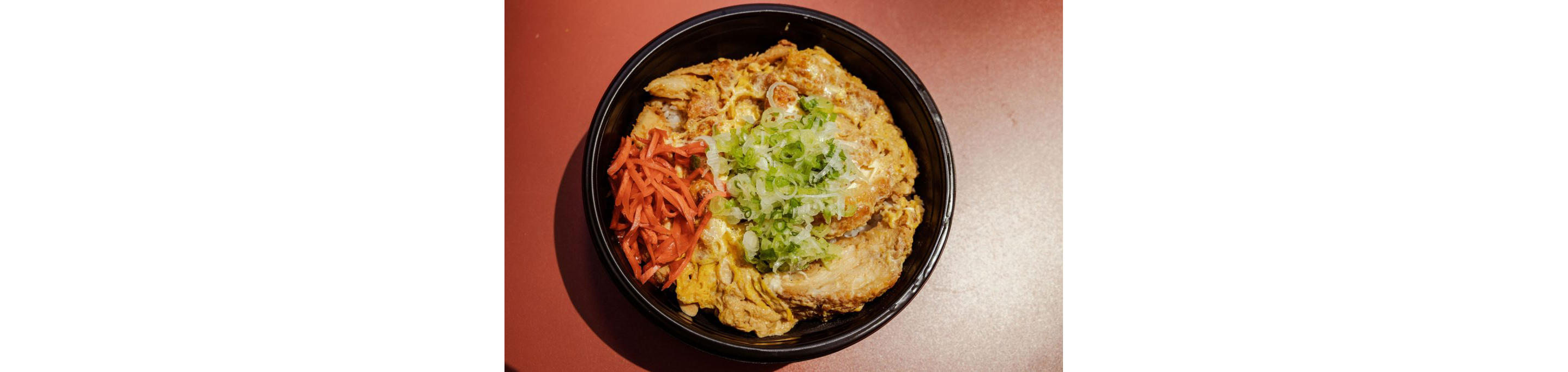 A large black bowl holding a Japanese dish.