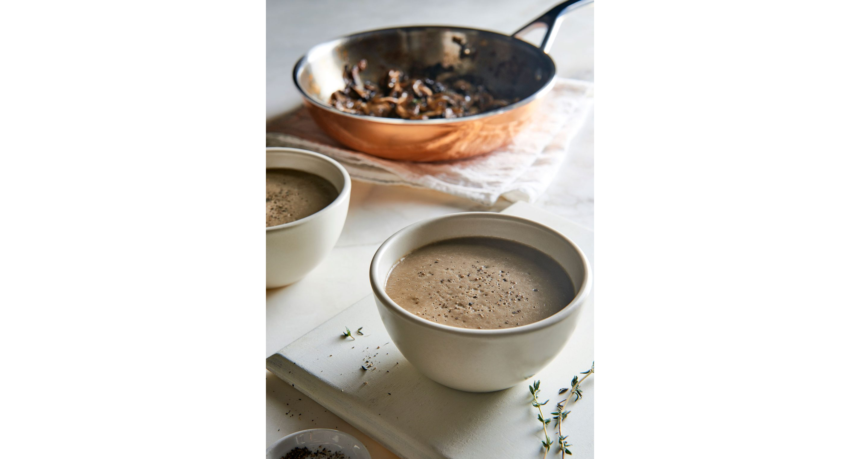 Two white bowls of creamy magic mushroom soup.