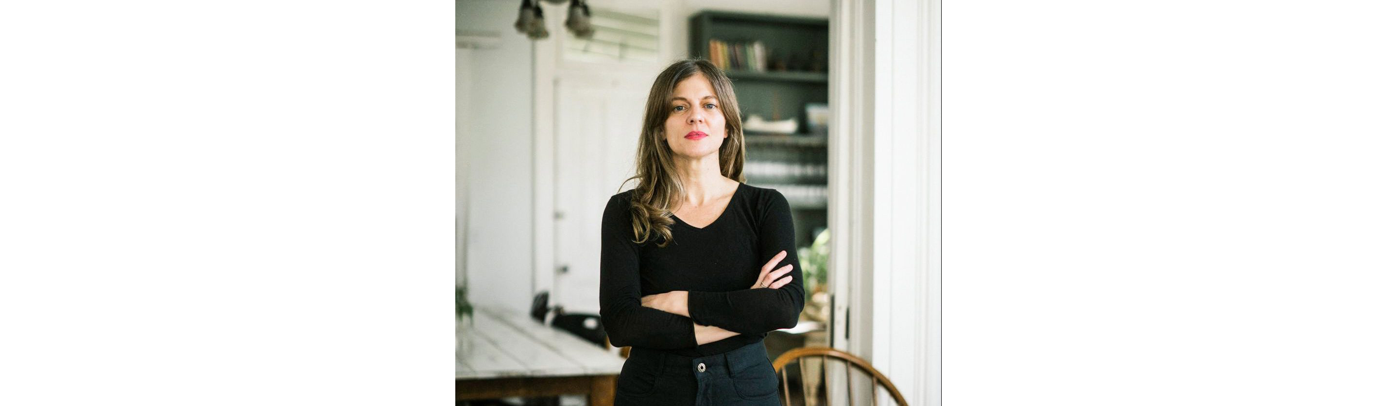 Melissa M. Martin standing with arms crossed behind a stake of white plates.