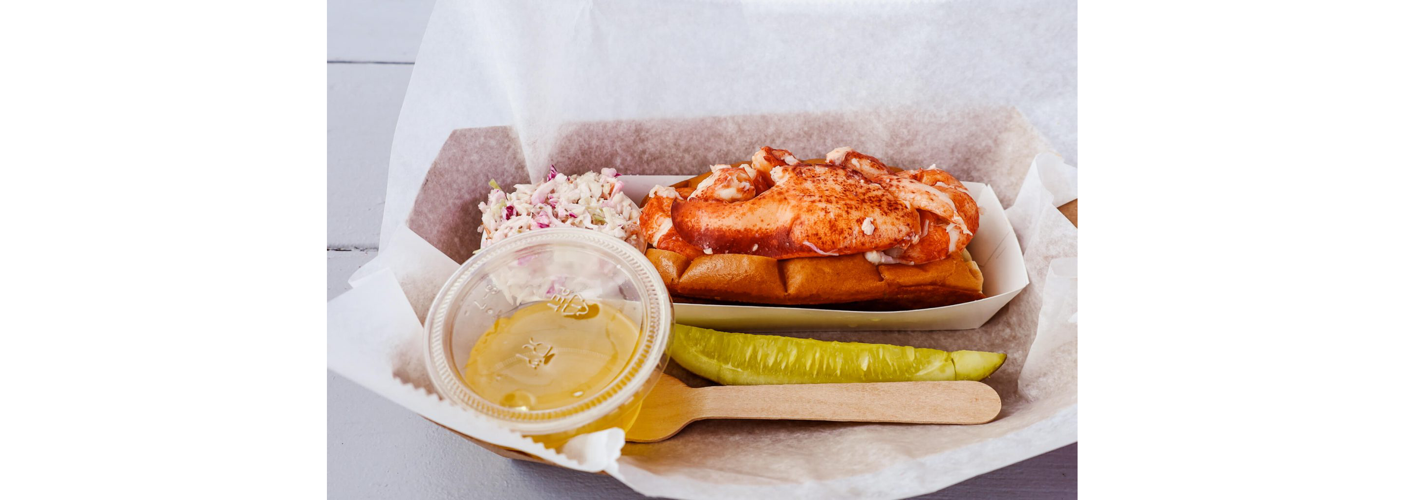 A lobster roll served with coleslaw.