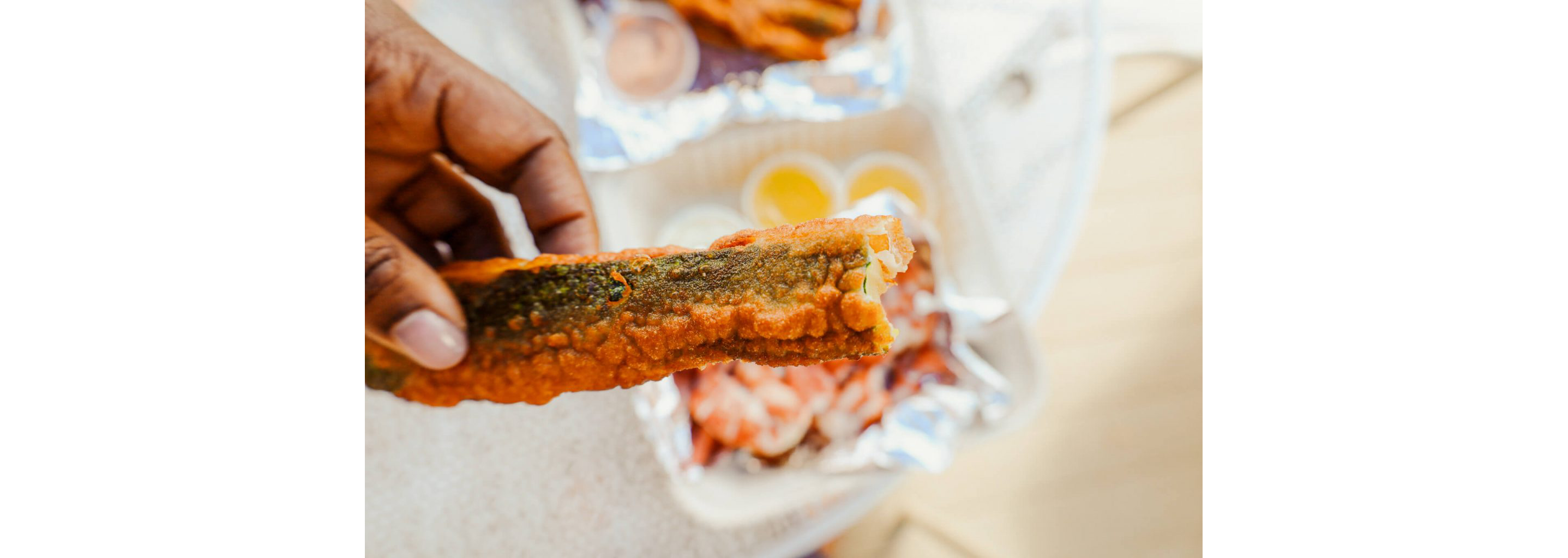 A person holding a fried zucchini.
