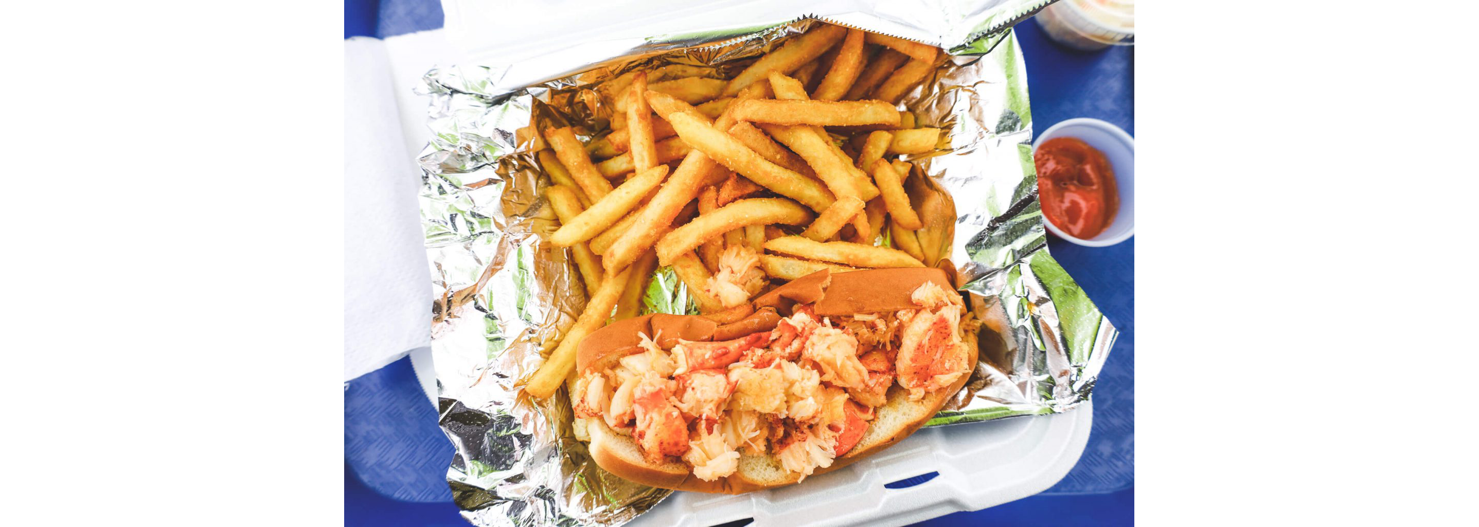 A lobster roll served with crispy french fries.