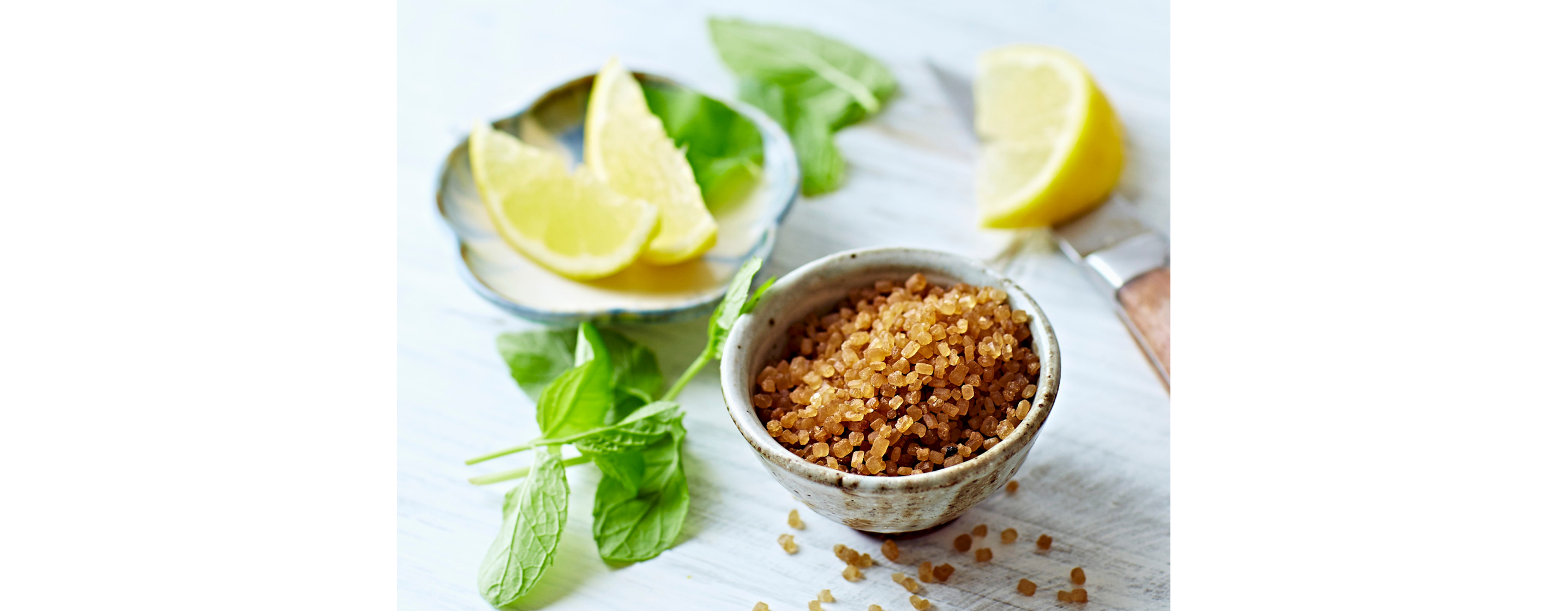 A small metal bowl of crushed herbs, with lemon wedges on the side.