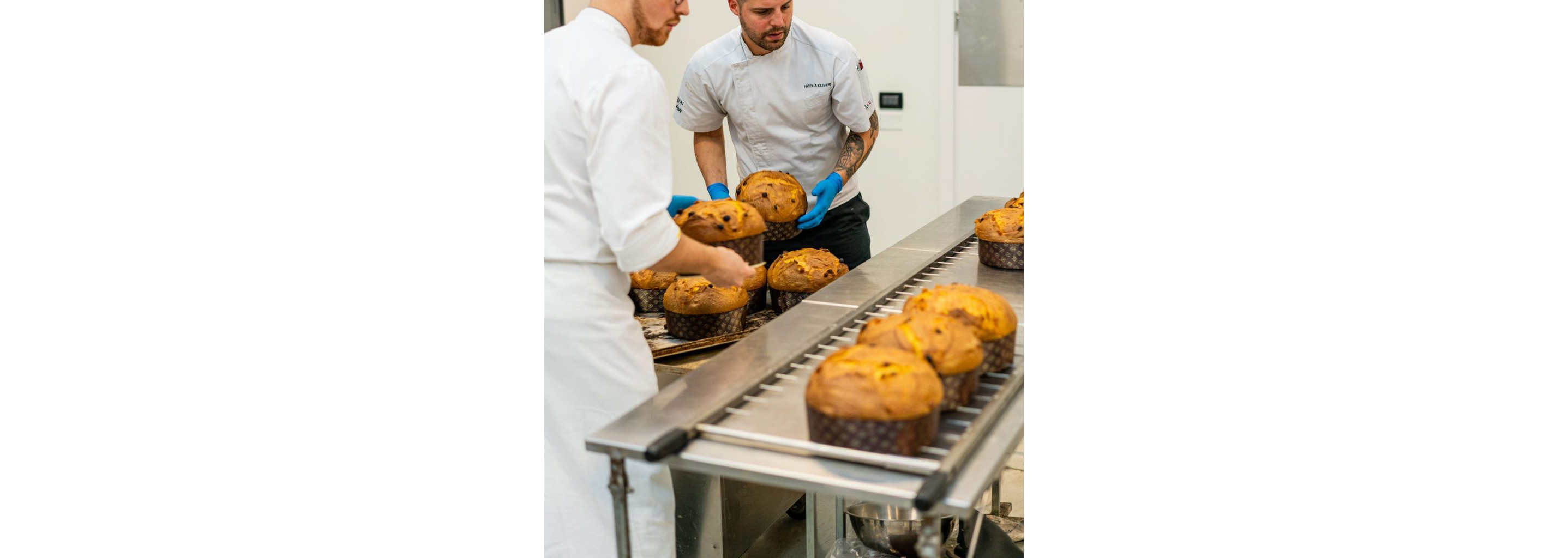 Bakers delicately handling baked panettones on an assembly line.