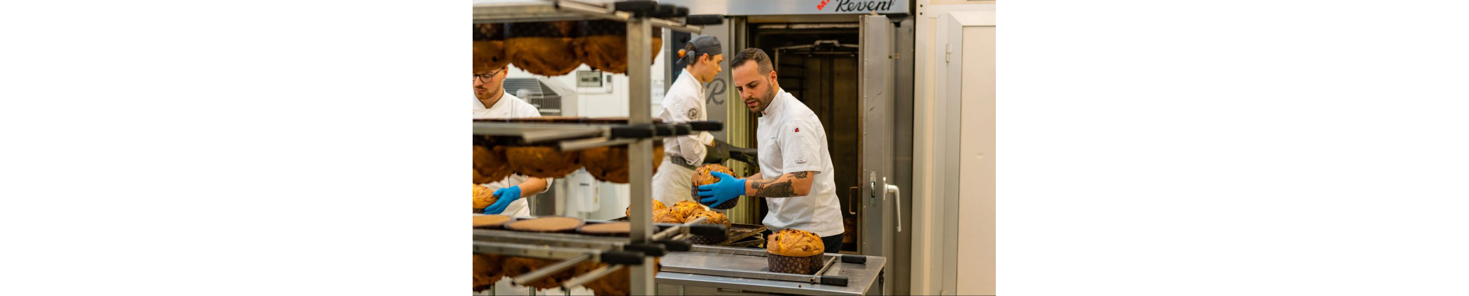 Olivieri handling freshly baked panettone loaves.