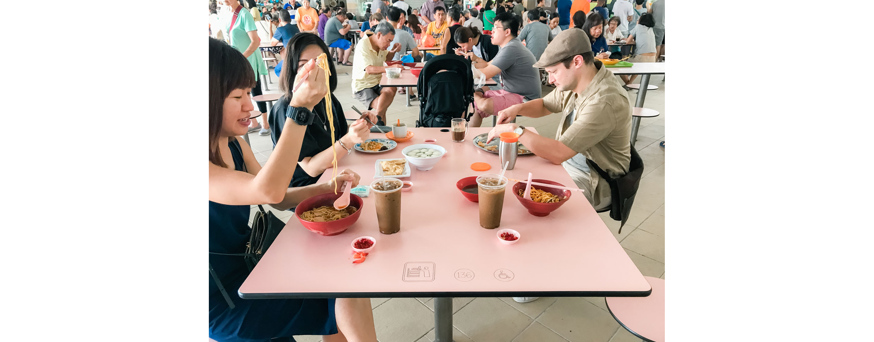 People sitting down eating at a communal table.