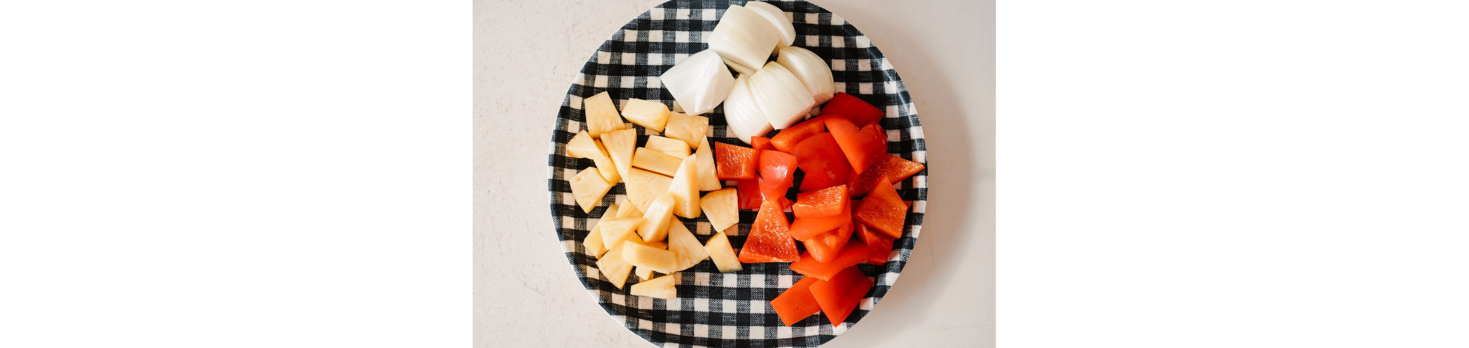 A plate of chopped onions, pineapples and red bell peppers.