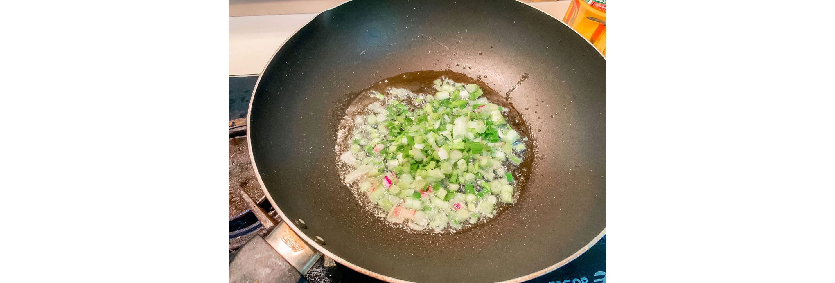 Chopped green onions frying in a wok.
