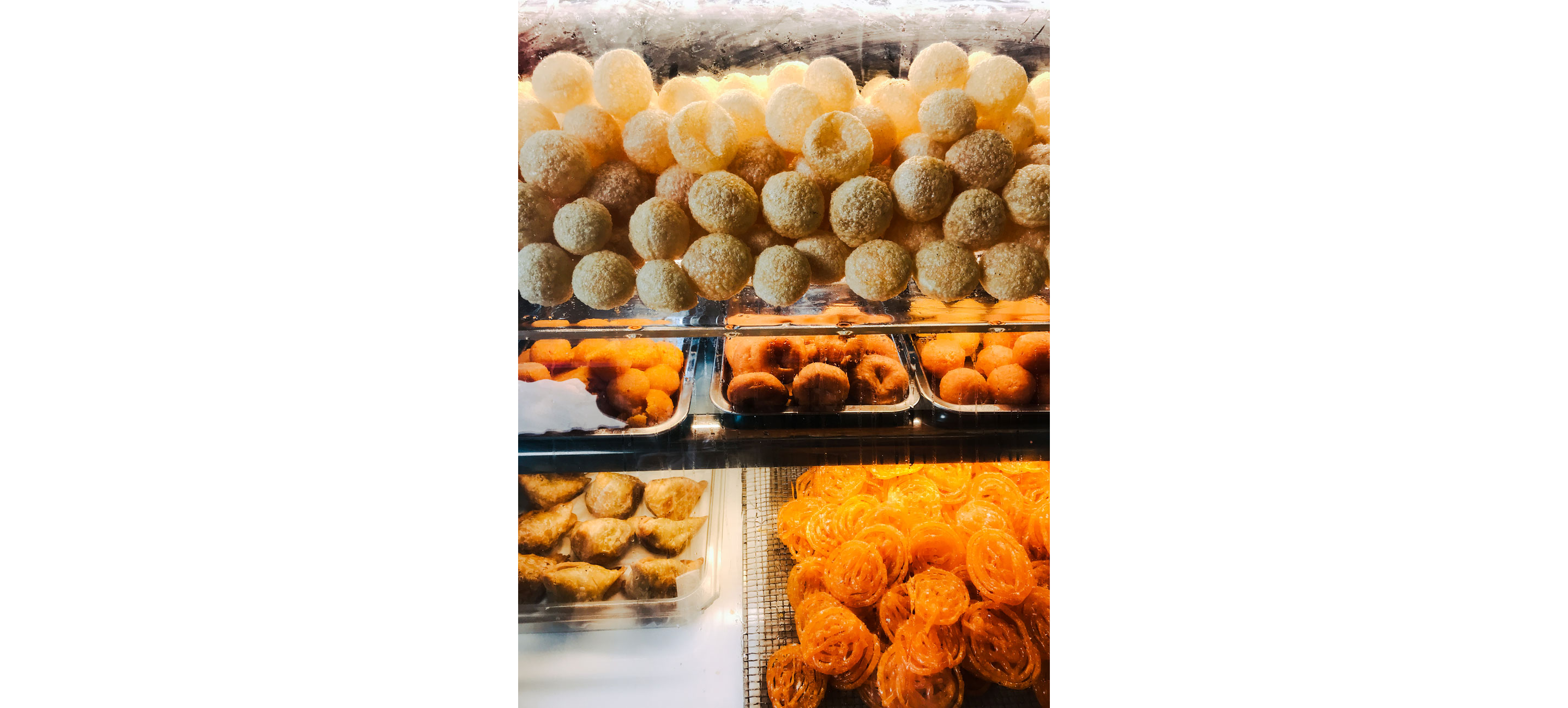 A display of sweets and puri, bite-sized deep-fried hollow dough balls.