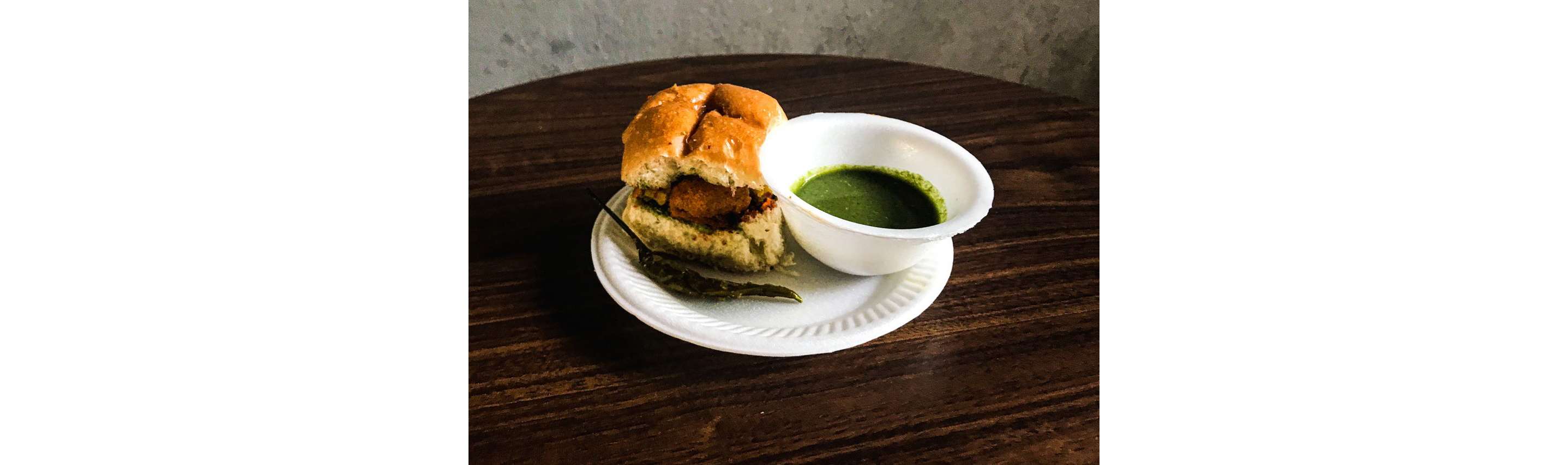 Vada pav, a spiced potato slider, resting on a plate.