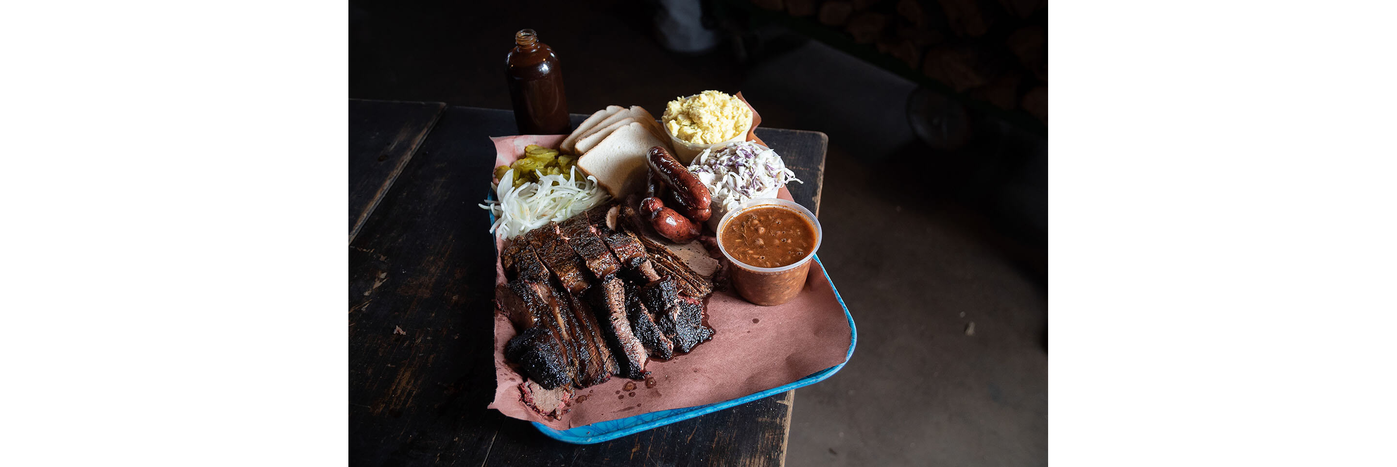 A tray of ribs ready to be served with baked beans, coleslaw and other fixings.