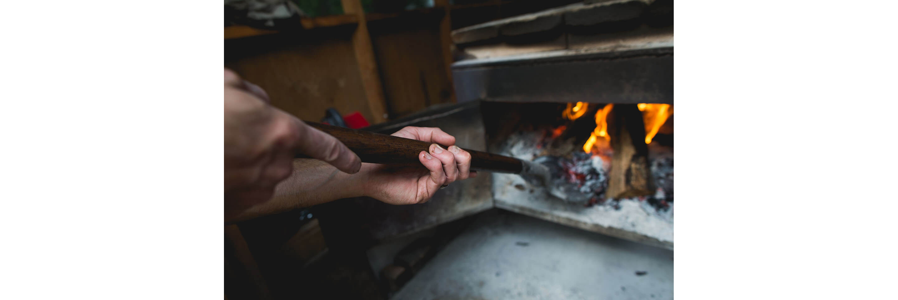 A person shoveling charcoal around in a charcoal-buring stove.