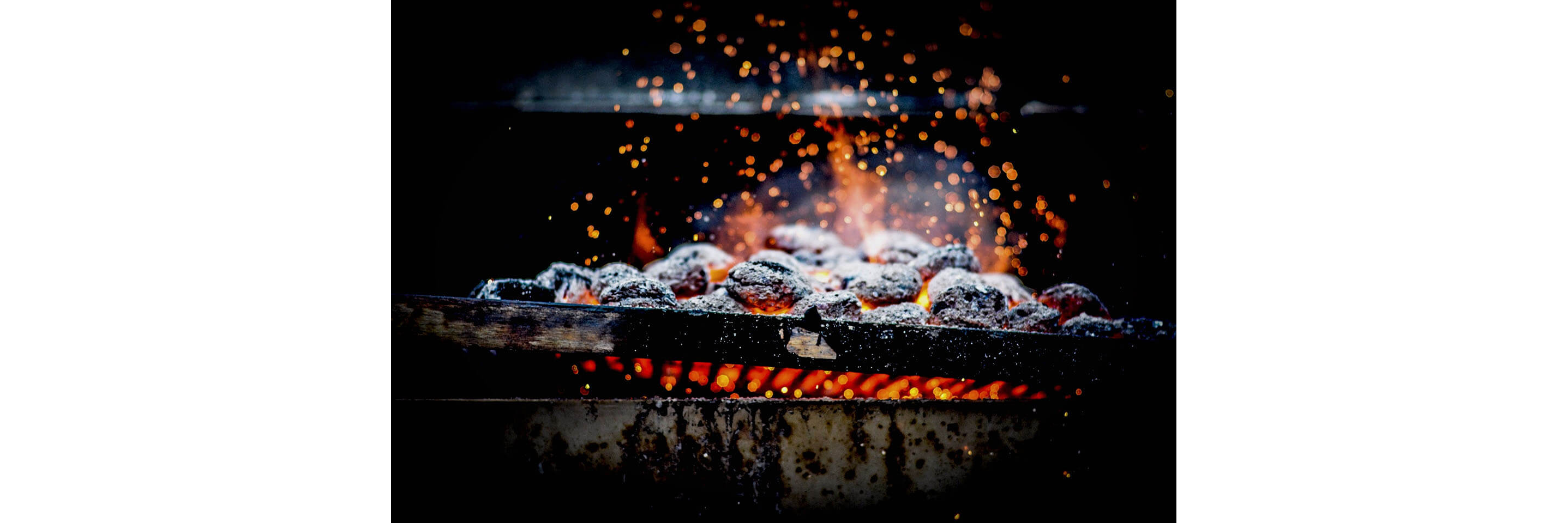 Charcoal burning into bright embers on a grill grate.