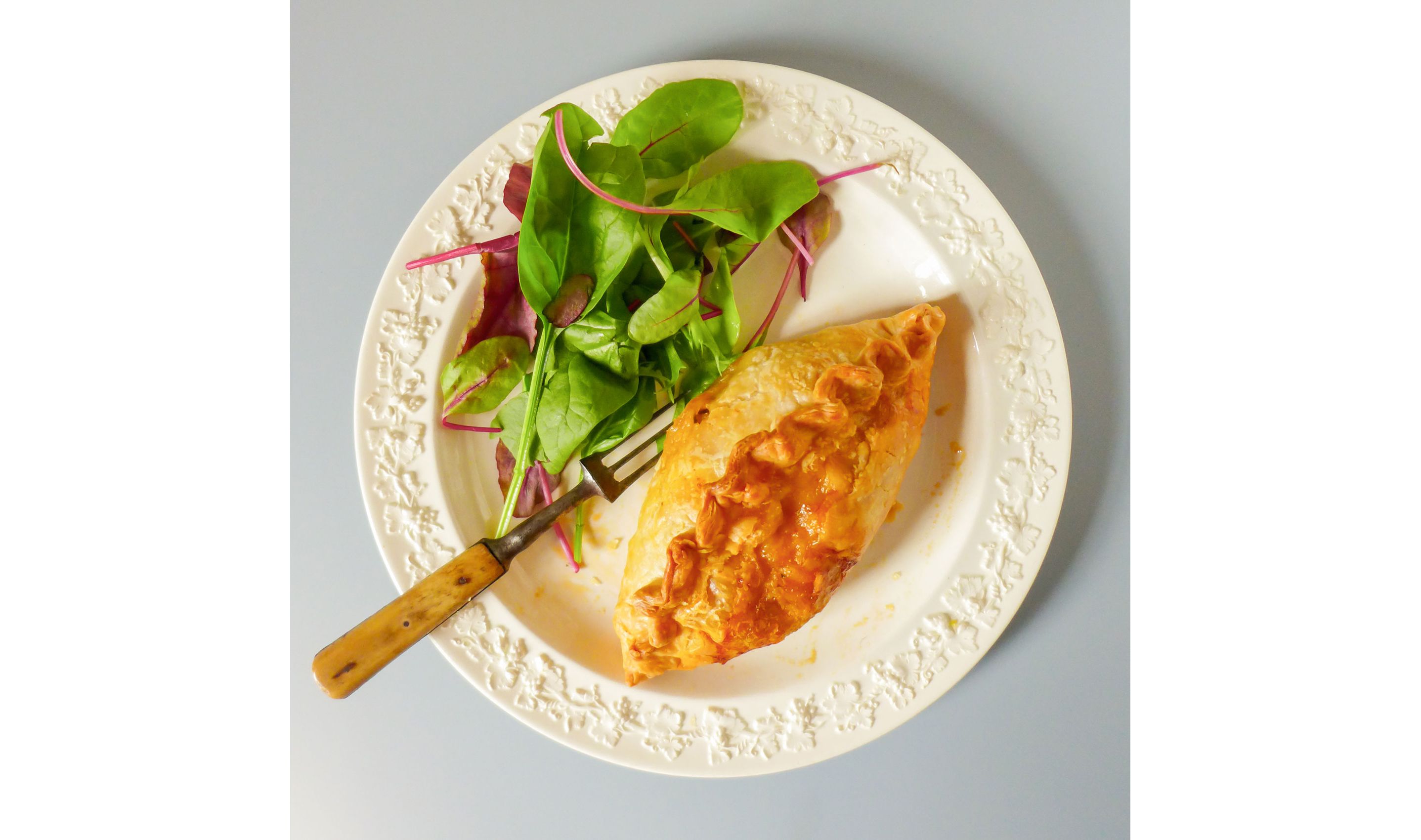 A toasted crab pasty resting on a plate.