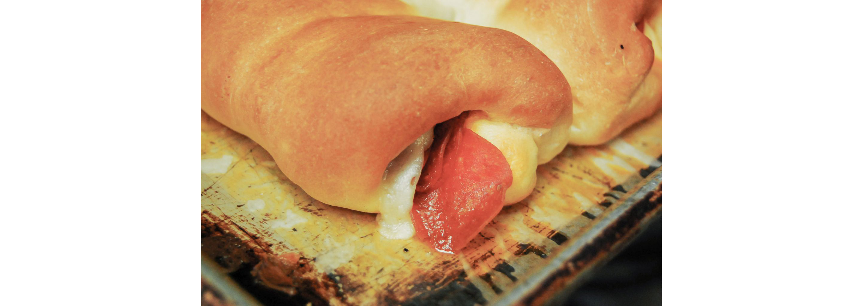 Cheese and pepperoni oozing out of a pepperoni roll.