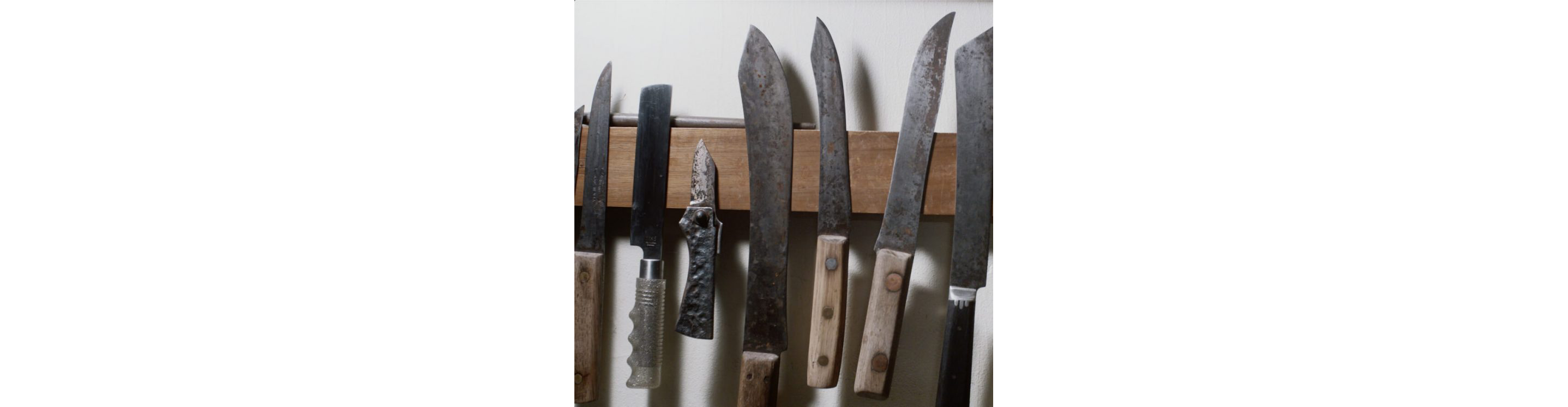 A variety of knives displayed on the wall.