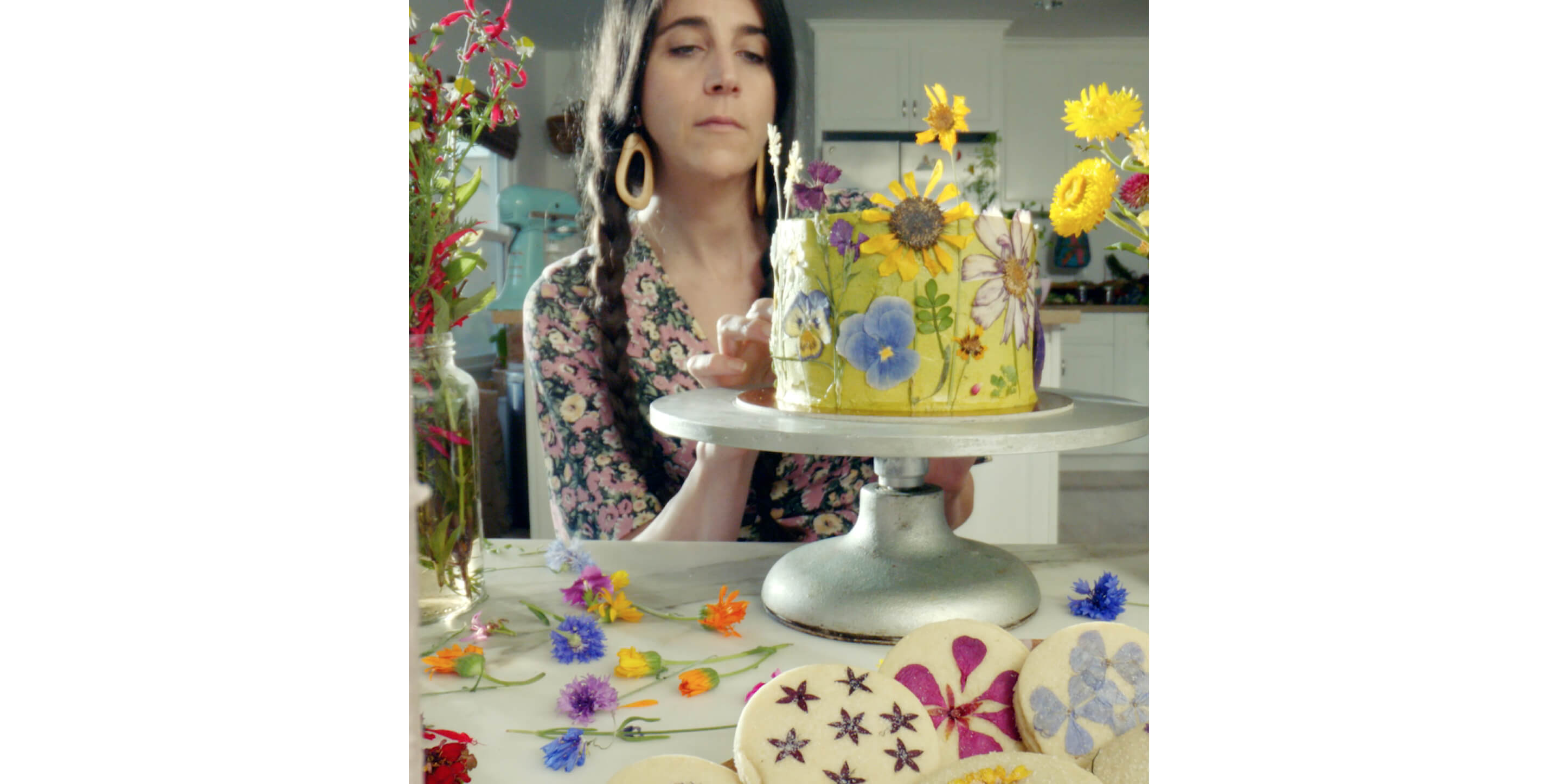 Loria Stern decorating a cake with edible flowers.