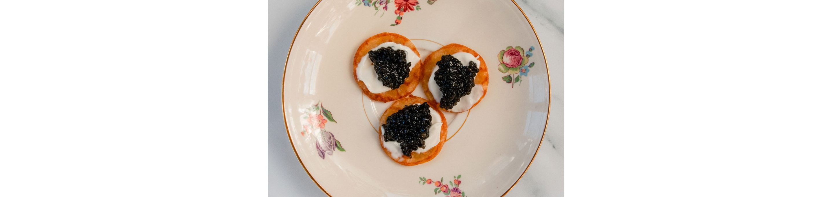 Dollops of black caviar resting on top of freshly made blinis.