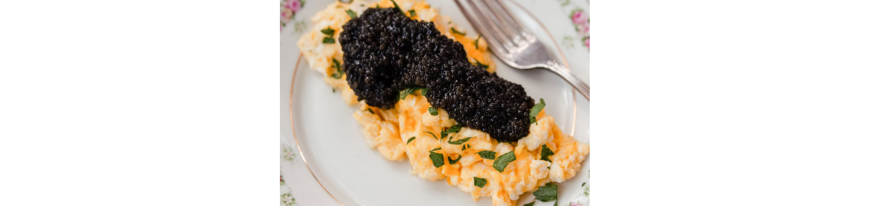 A hefty serving of black caviar resting on top of scrambled eggs.