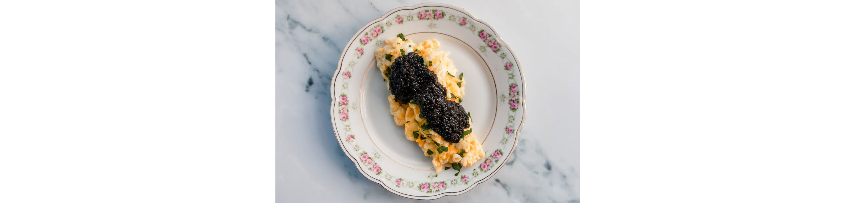 A plate of scrambled eggs topped with black caviar.