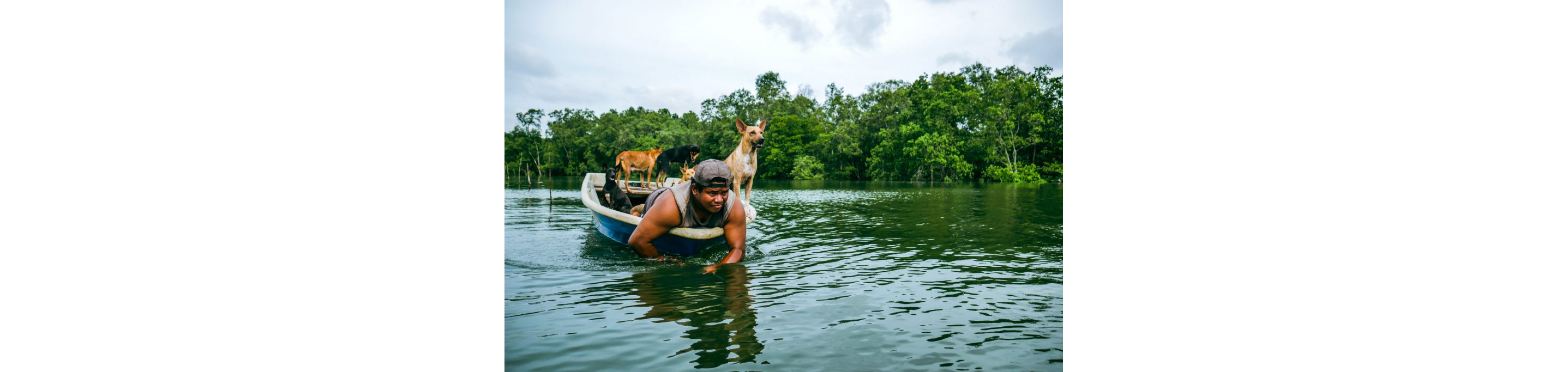 A young man on a boat with his dogs.