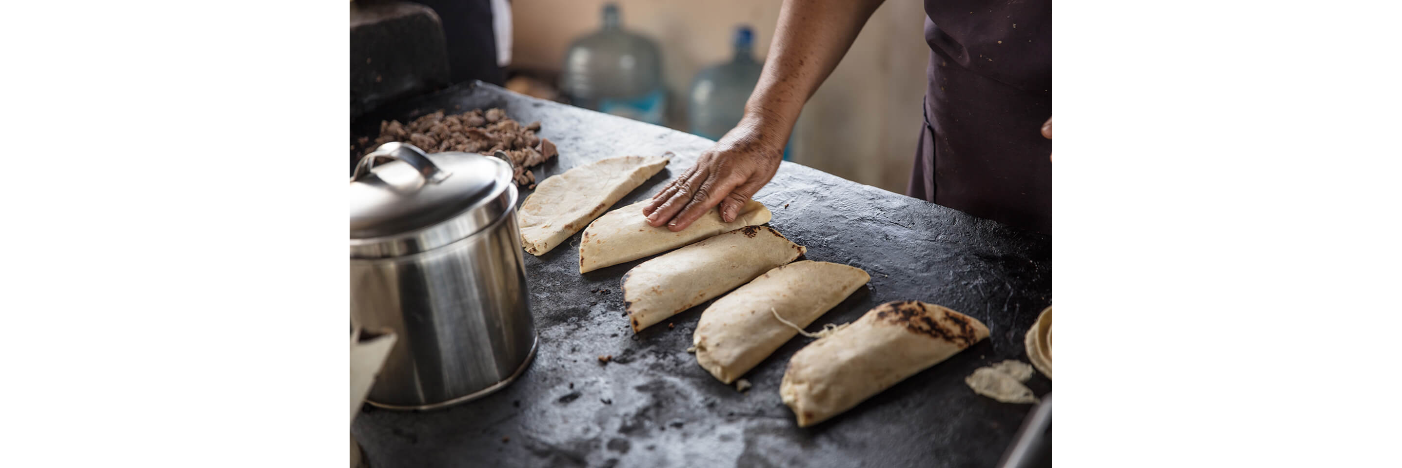 A person tending to folded flour tortillas.