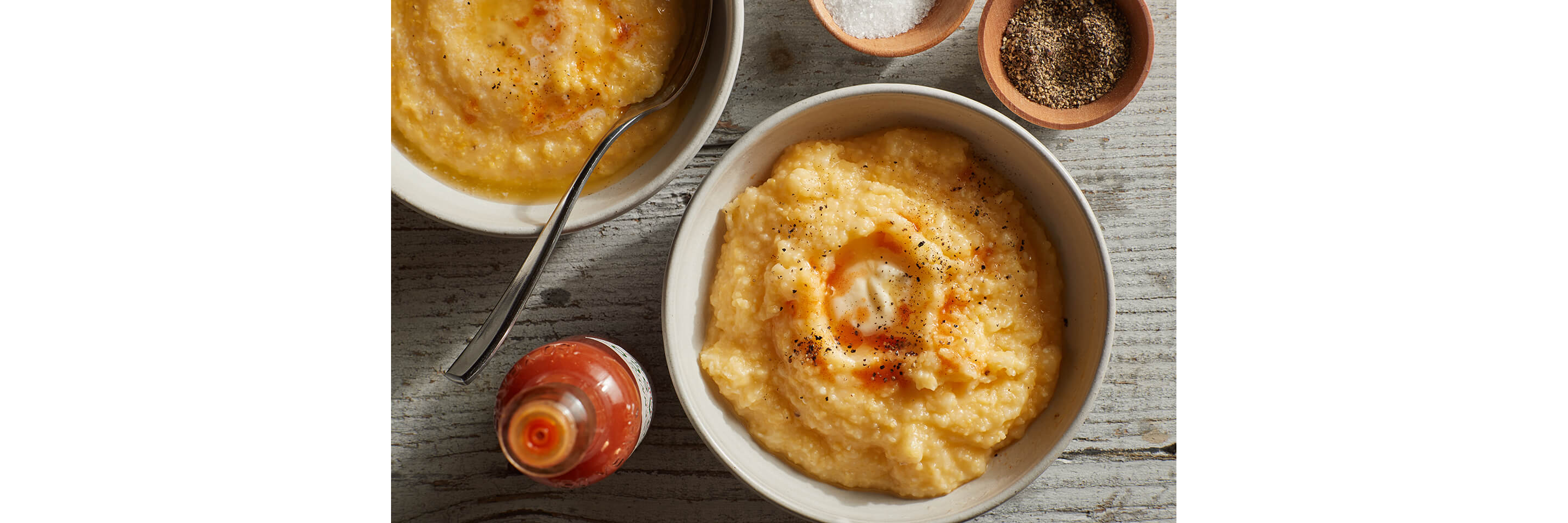 A bowl of creamy grits topped with hot sauce.