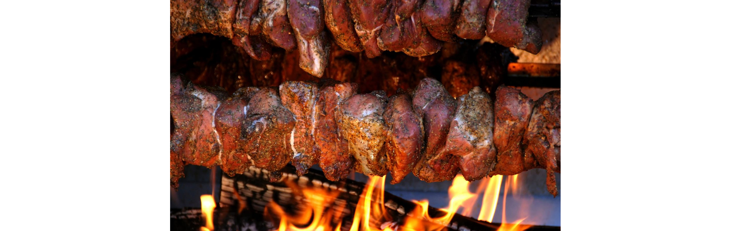 Rotisseried pork gently cooking over a low flame.