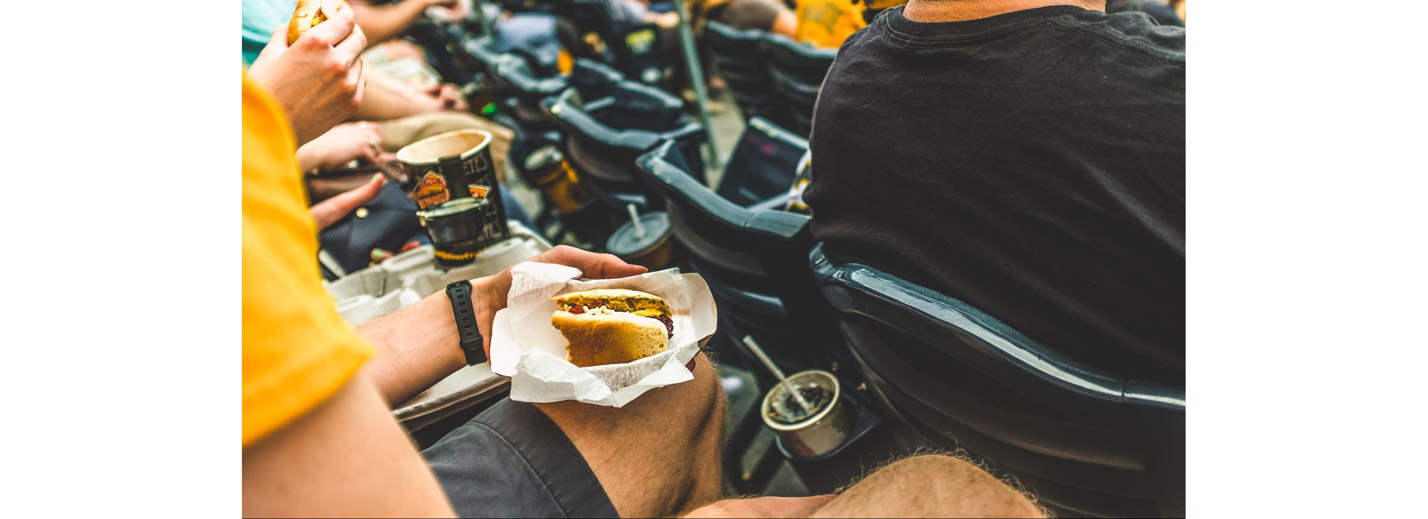 A person eating oversized hot dog in a baseball stadium.
