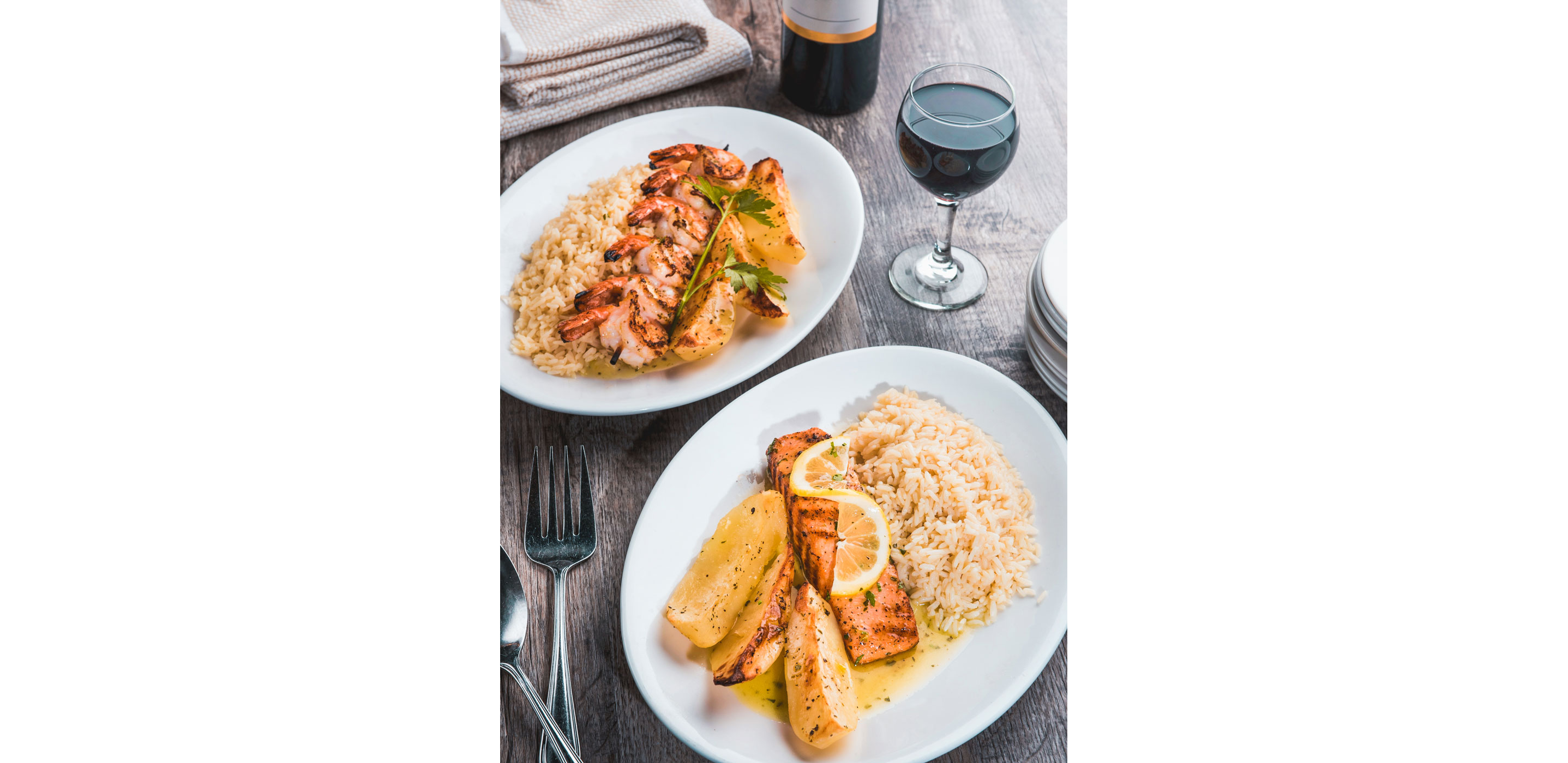 Two plates filled with seafood, rice and potatoes.
