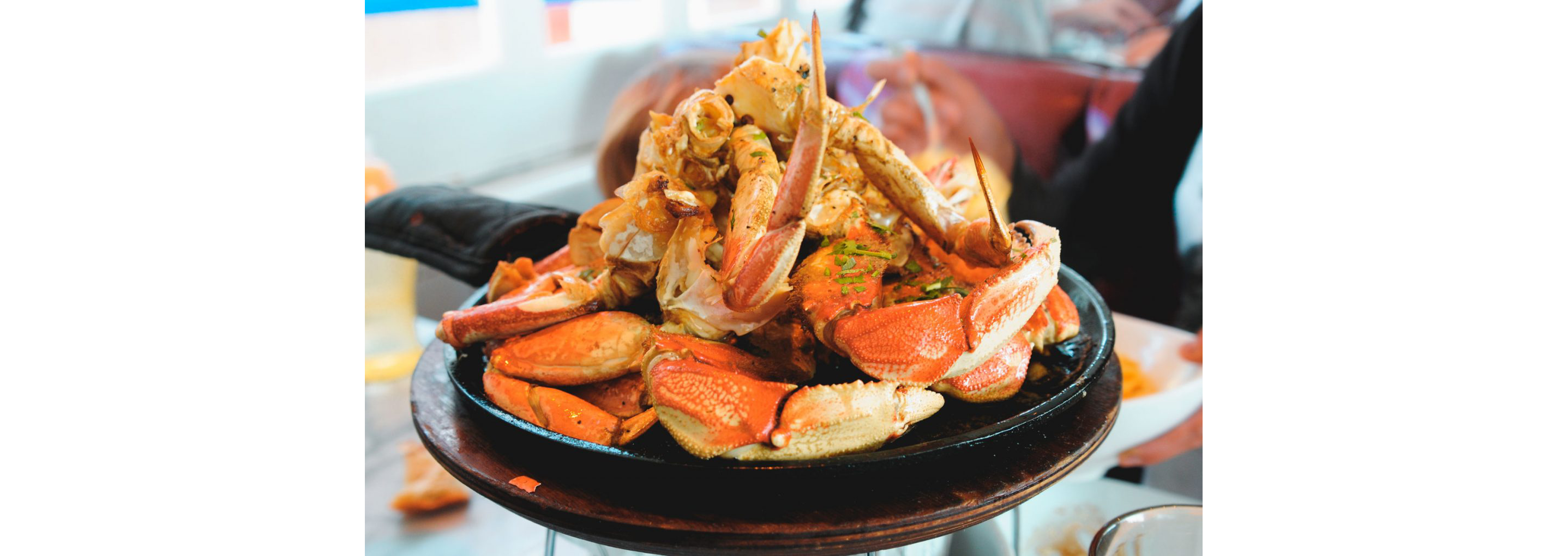 A cast iron skillet filled with steamed crab legs.