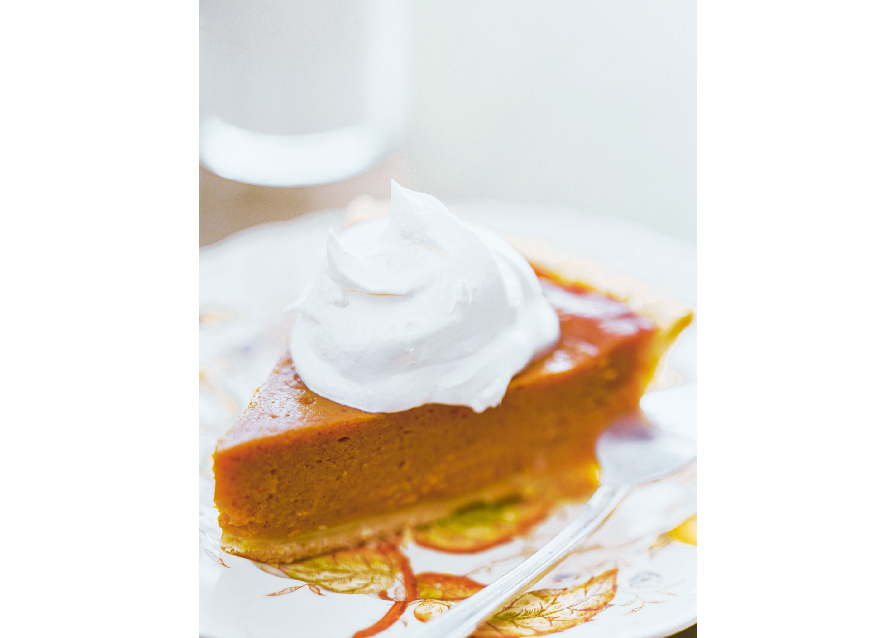 A clean slice of sweet potato pie with a huge dollop of whip chream.