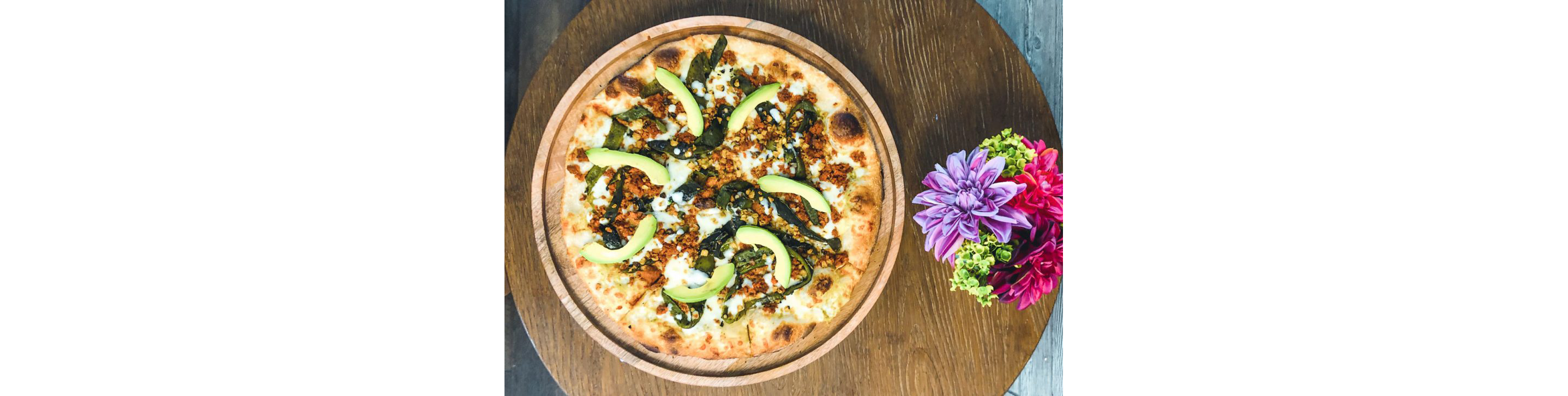 A wooden dish holding a Mexican pizza.